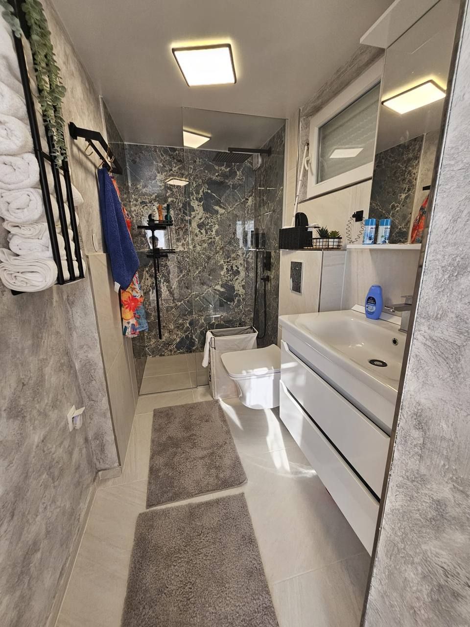 Modern bathroom with rain shower and natural stone wall