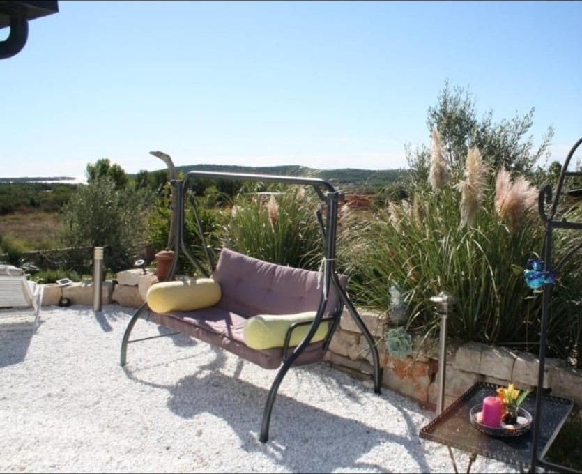 Hollywoodschaukel im Kiesgarten mit Pampasgras und Meerblick in der Ferne