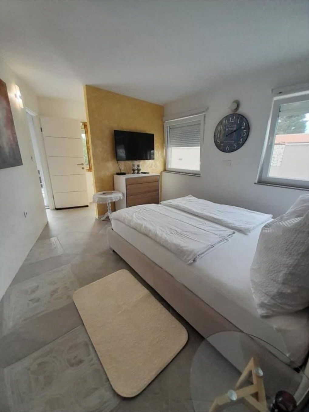 Bright bedroom with double bed and wall clock